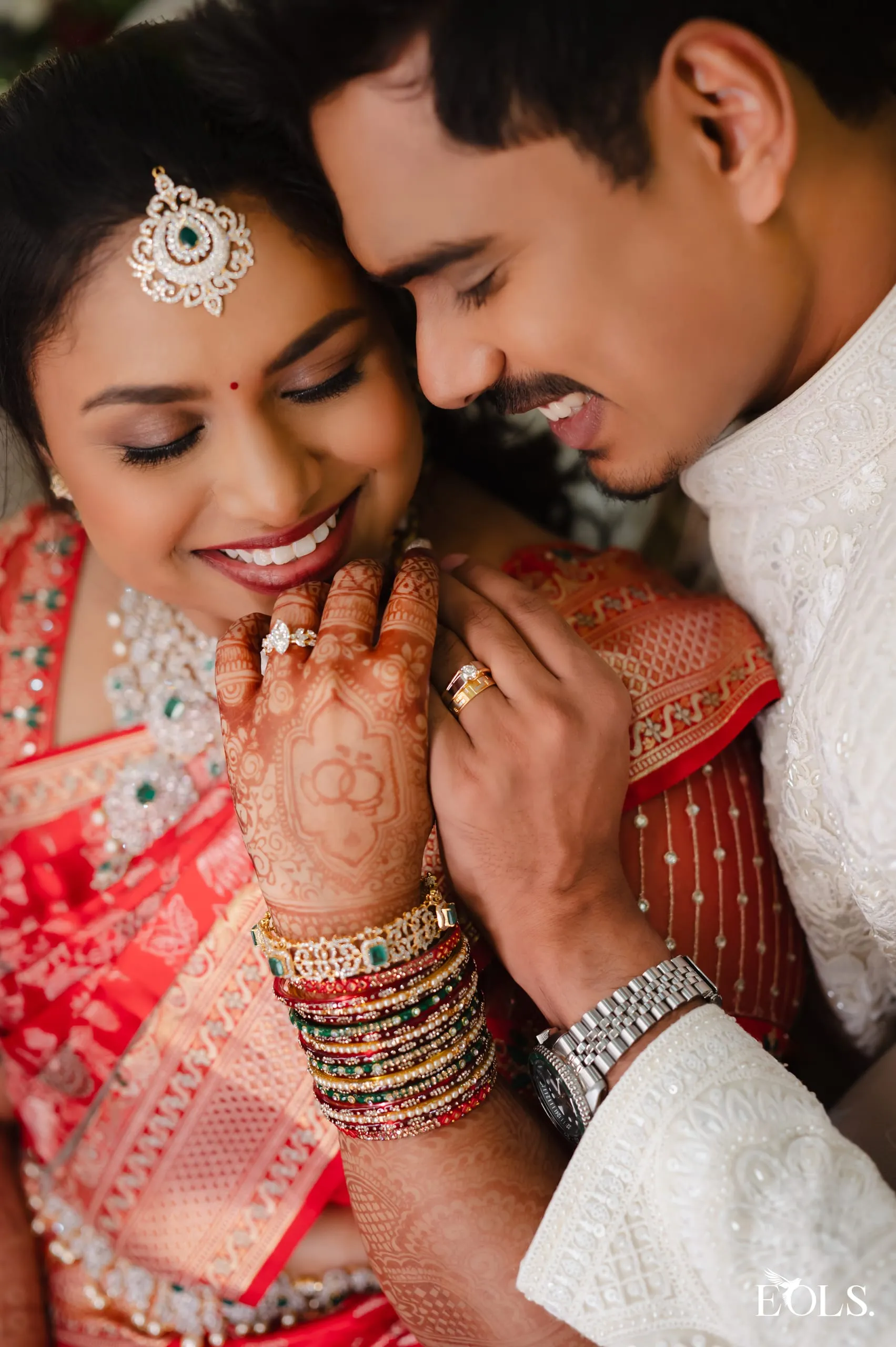 A woman raises her hennaed hand to show an engagement ring.