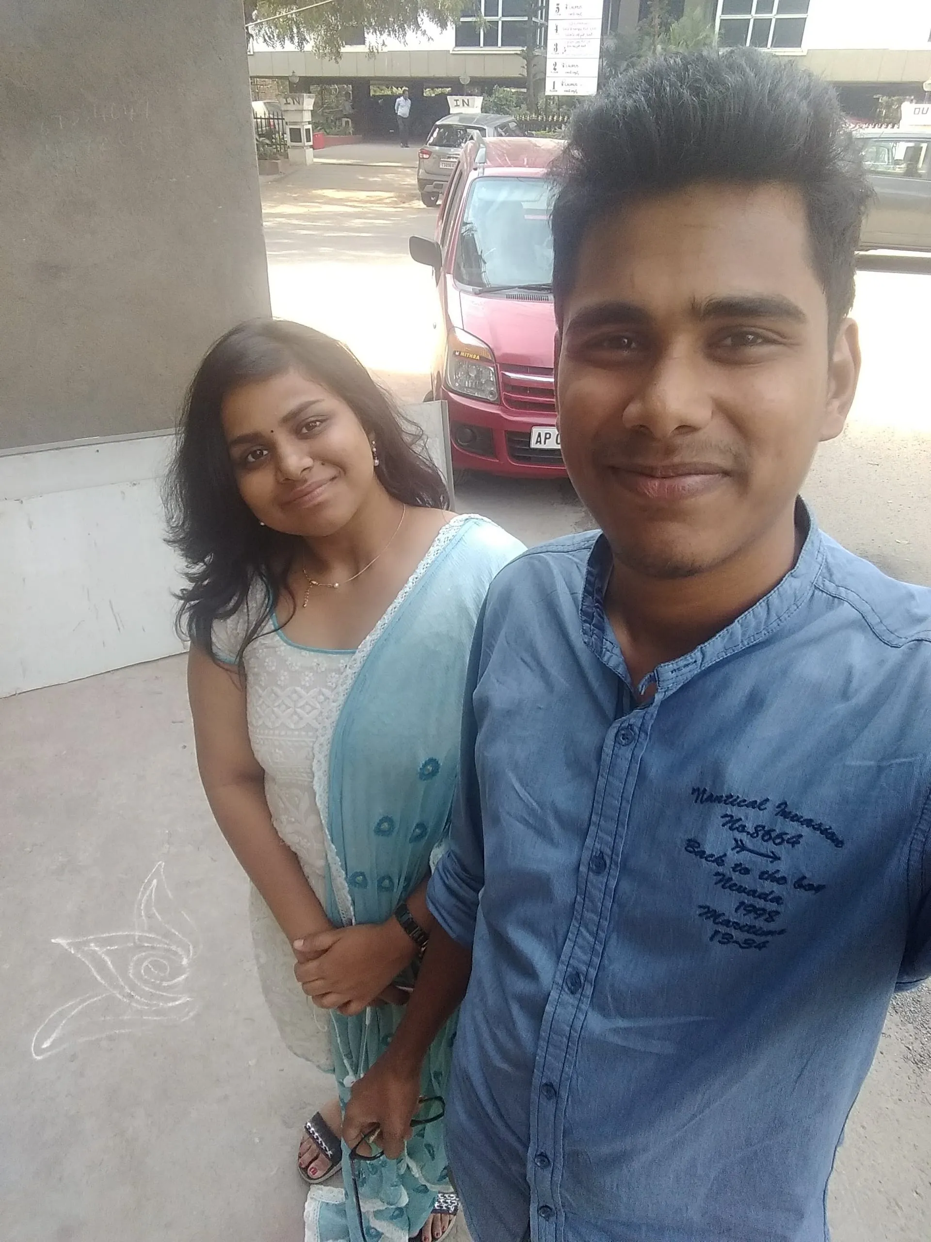 Two friends smiling outdoors near a parked car.