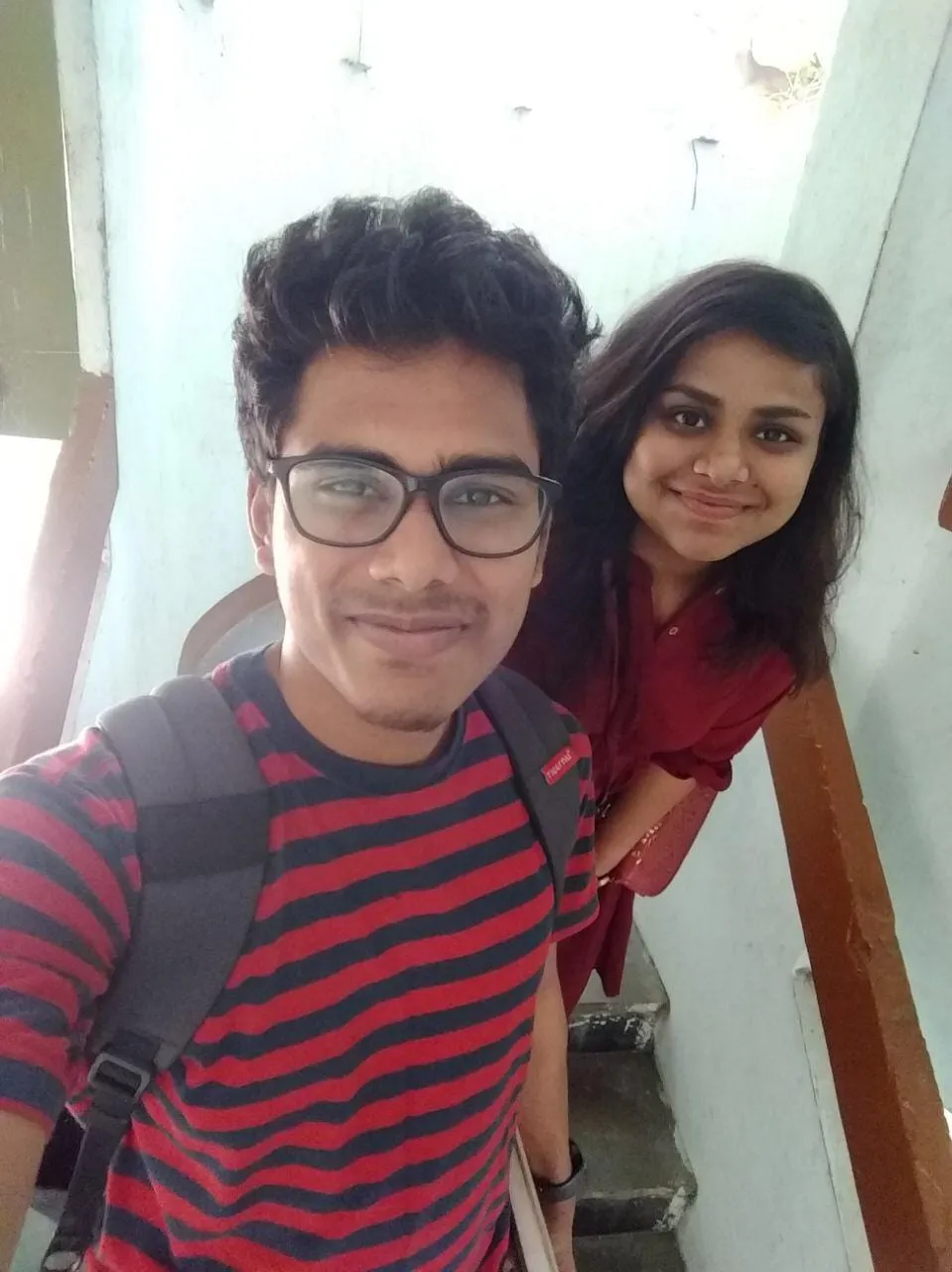 Two friends on a staircase, one with a backpack.