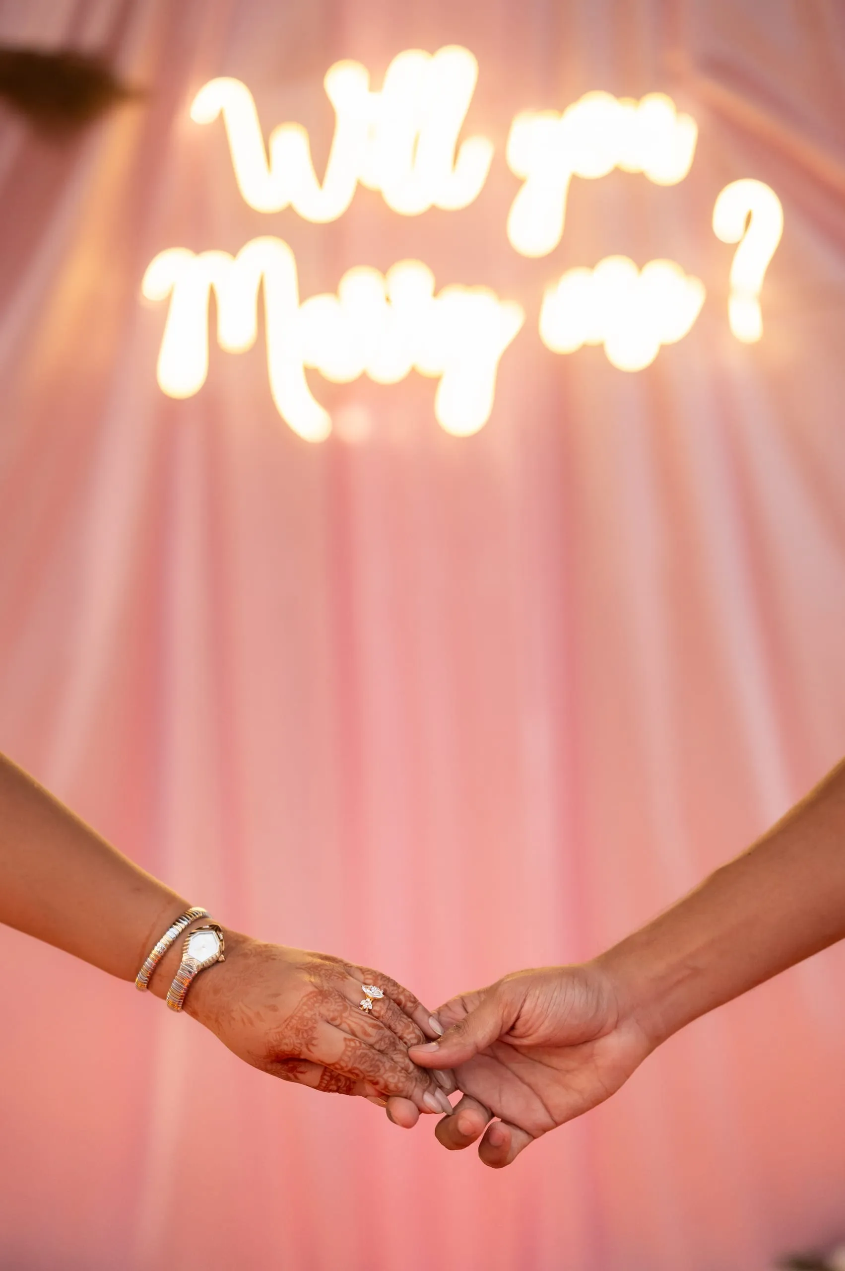 The neon "Will you marry me" sign and joined hands