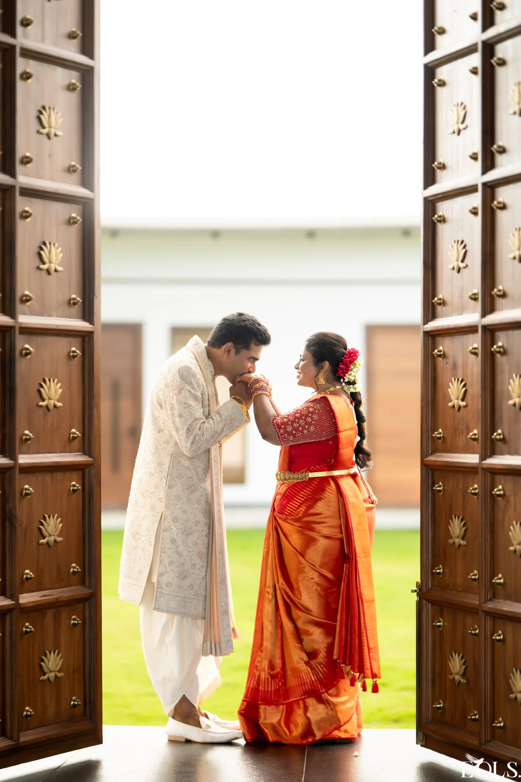 A couple framed between tall open carved doors.