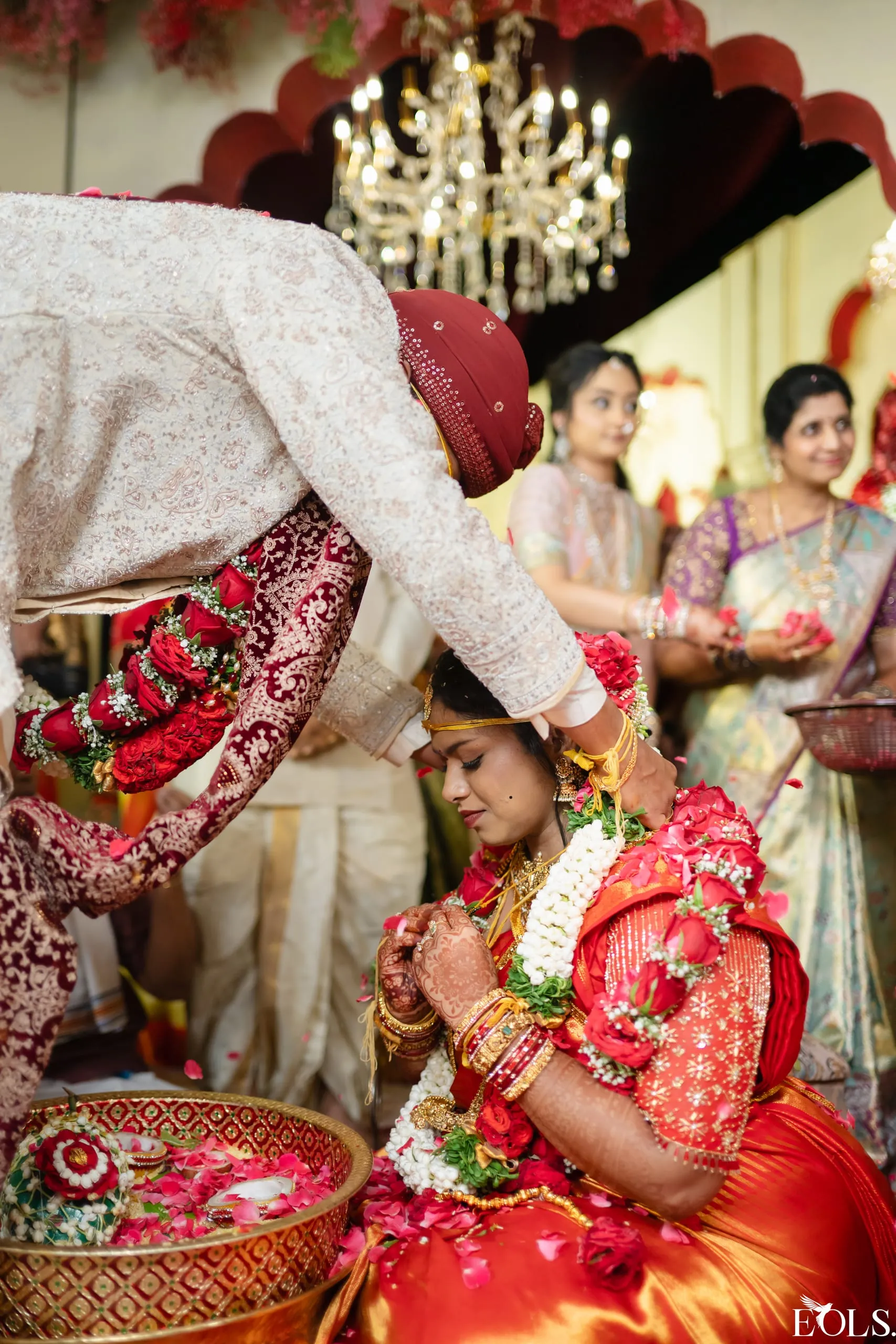 A groom places a garland on the seated bride during a ritual.