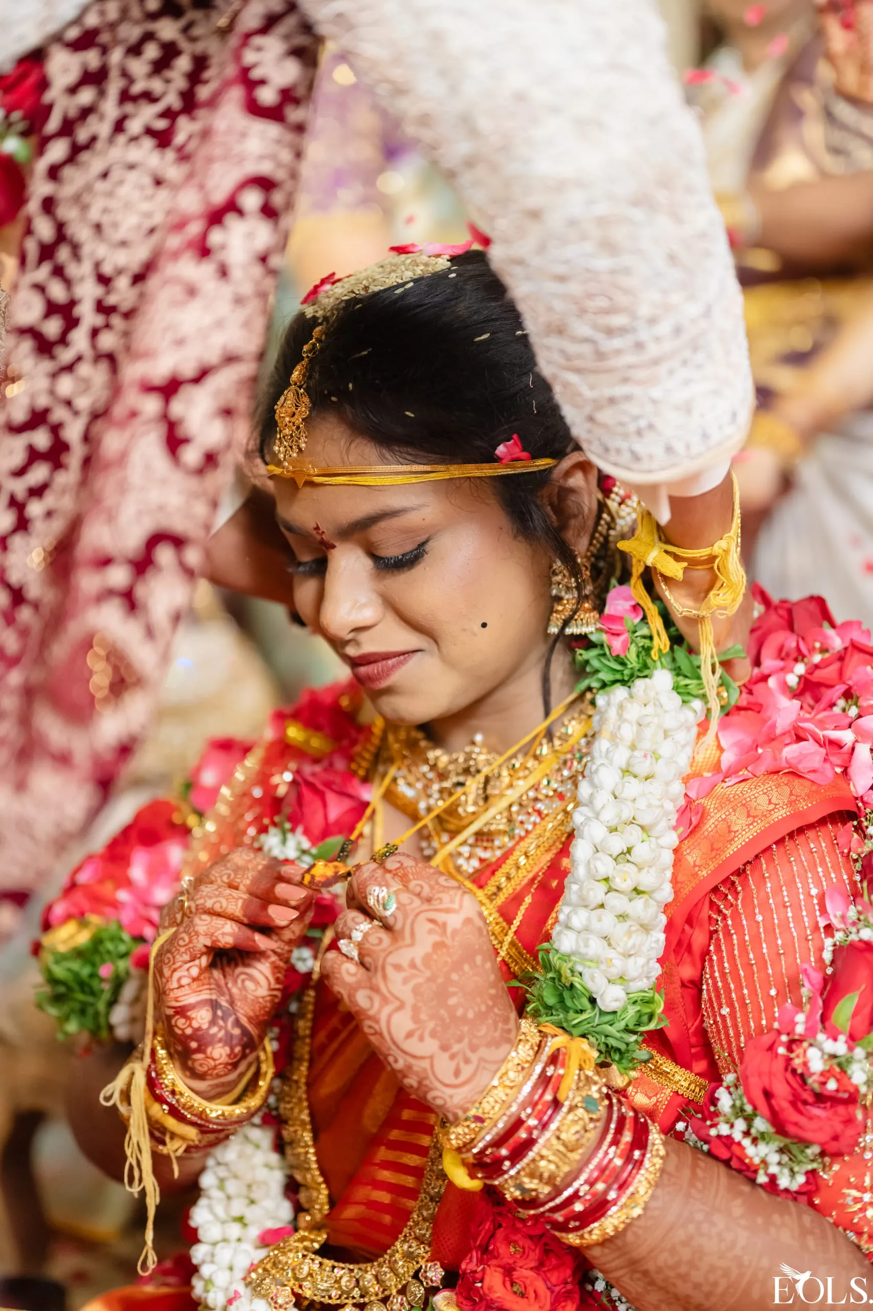 A close portrait of the bride in a red saree with henna and jewellery.
