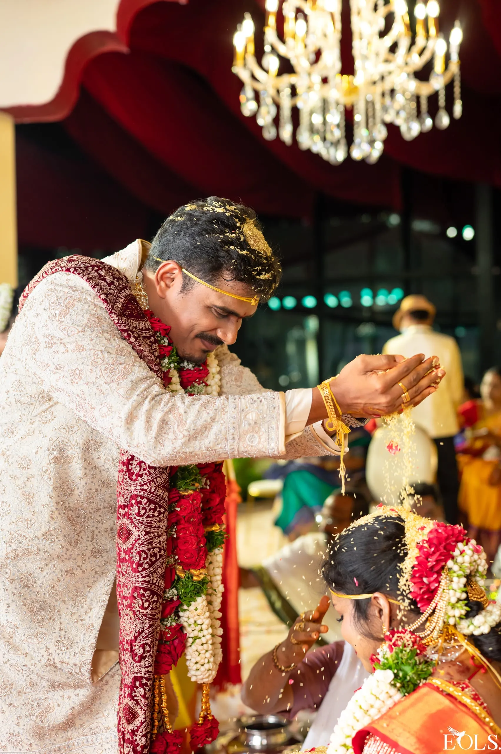 A groom pours rice over the seated bride during a ritual.