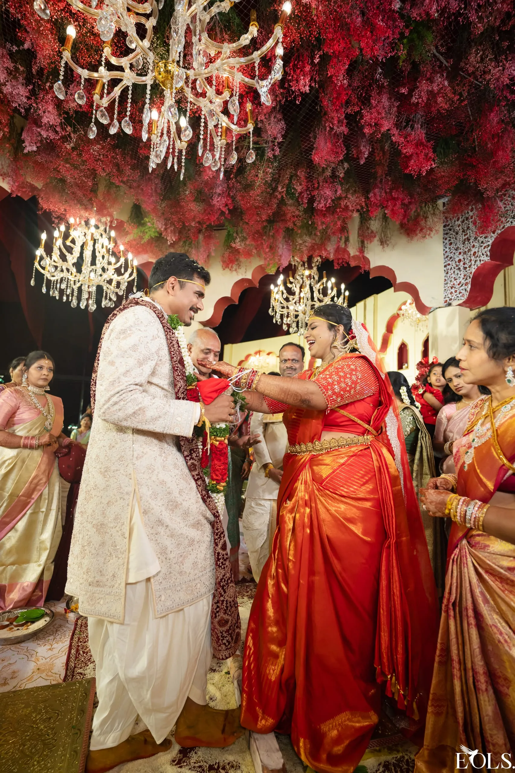 A bride laughs during a garland ritual among family.
